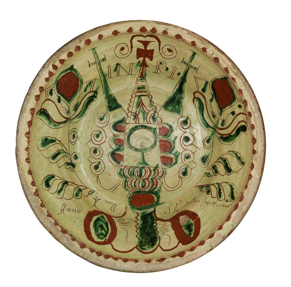 Tönisberger Teller von 1735 mit Kreuz und Ornamenten in Grün und Rot auf hellem Grund.