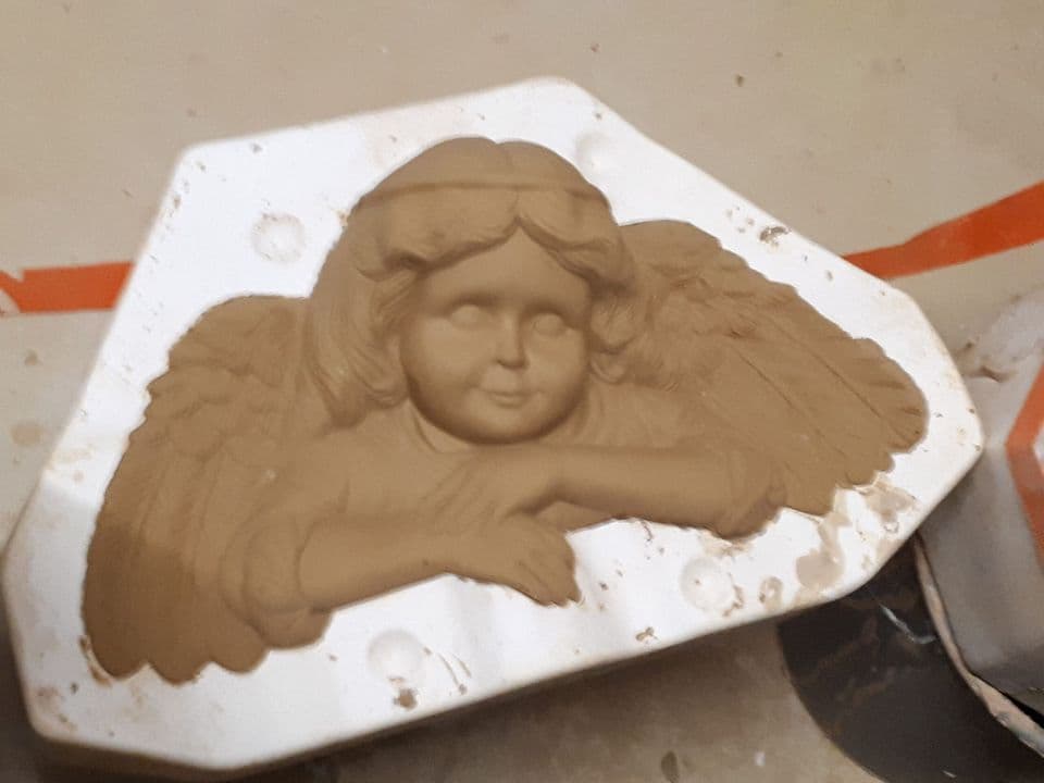 Ein Engelsrelief aus Ton in der weißen Gipsform.