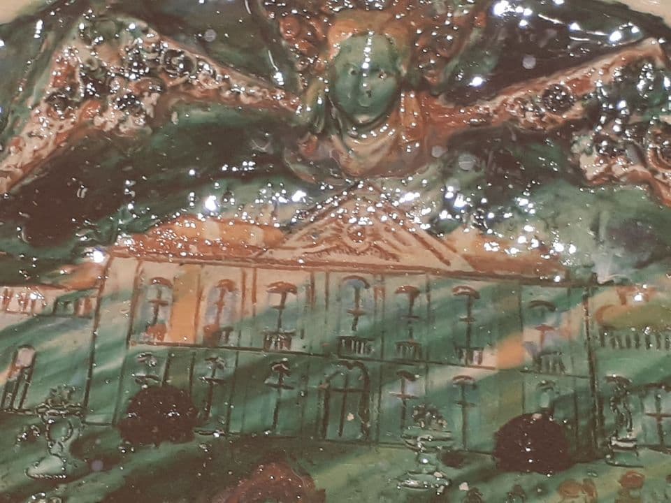 Detail der glasierten Schlossfassade mit Maske darüber, Glasur in Grün und Braun.