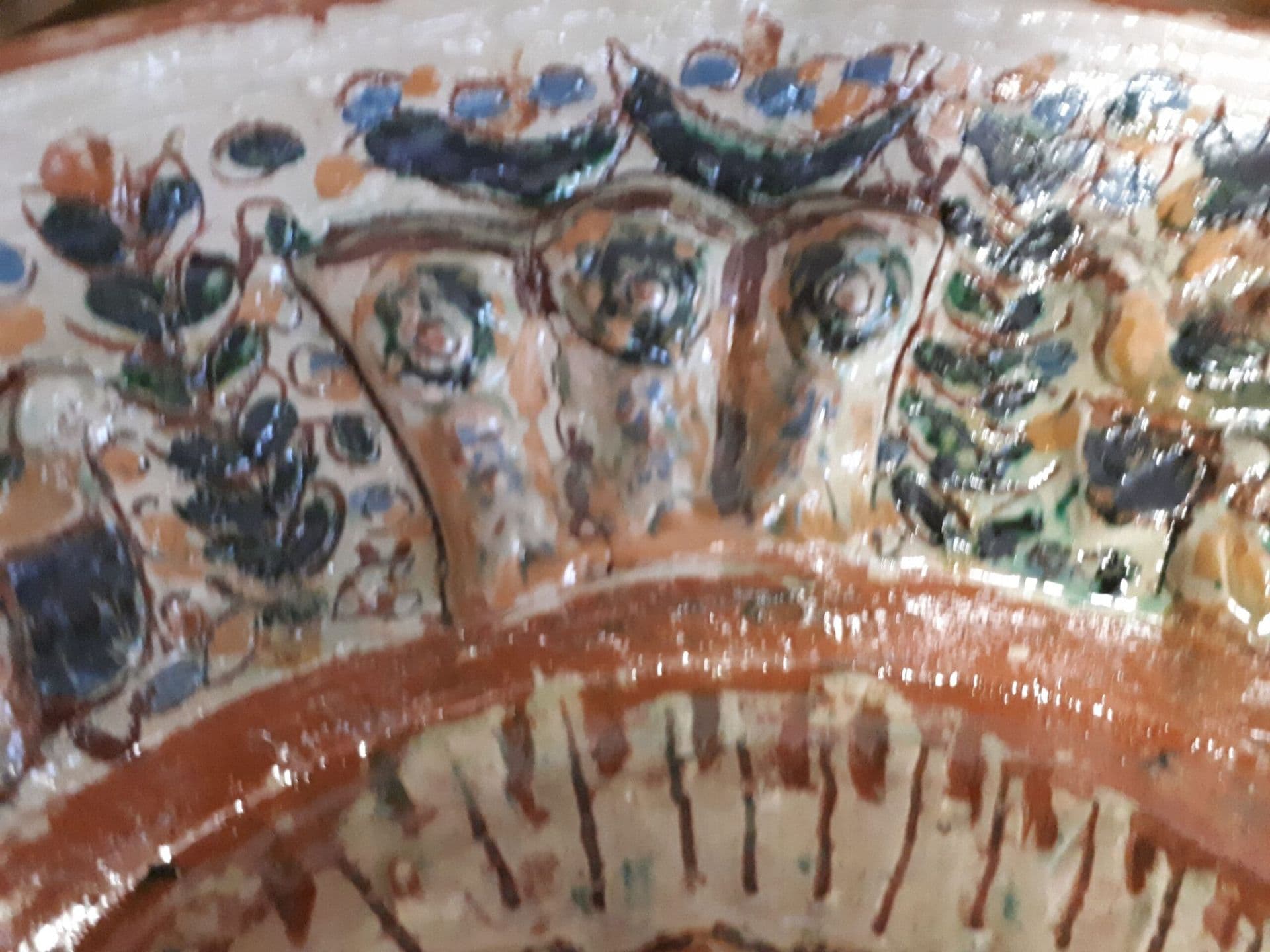 Nahaufnahme des Reliefs am Tellerrand mit blauen und grünen Blüten.