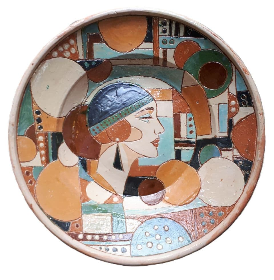 Teller im Art-déco-Stil mit Frauenprofil und Kappe vor Kreisen und Flächen in Orange, Türkis und Braun.