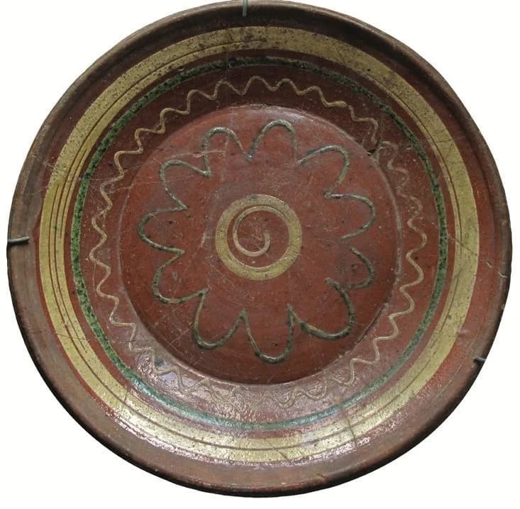 Tönisberger Teller des 19. Jahrhunderts mit Blütenrosette und Linienbändern auf rotbraunem Grund.