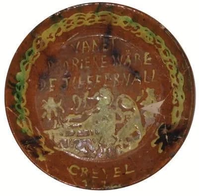 Teller mit Reliefdekor und der Aufschrift „Crefeld“ auf brauner Glasur.