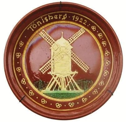 Teller mit Windmühle und der Aufschrift „Tönisberg 1922“, gelbe Engobe auf rotbraunem Grund.