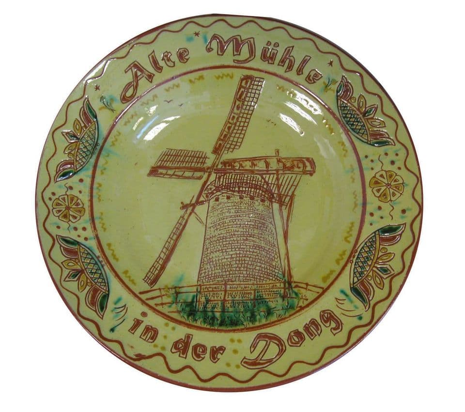 Teller mit Windmühle und Schriftzug „Alte Mühle in der Dong“ auf leuchtend grüner Glasur, Rand mit Blatt- und Punktornamenten.
