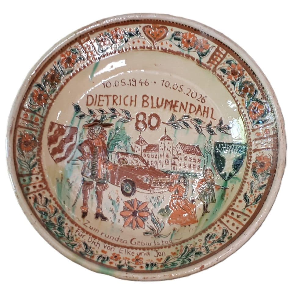Teller zum 80. Geburtstag mit Ortsansicht, altem Auto und Wappen, Blumenbordüre am Rand, Name und Daten in Schrift.