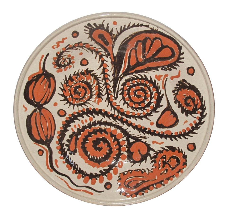Weißer Teller mit großem Ornament aus Spiralen und Blattformen in Rostbraun und Schwarz.