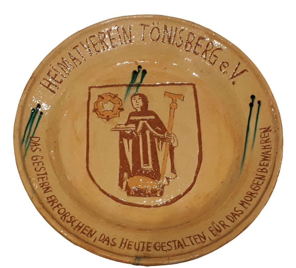 Teller mit Wappen des Heimatvereins Tönisberg, darin ein Heiliger mit Attributen; Vereinsname und Leitspruch als Ritzschrift am Rand.