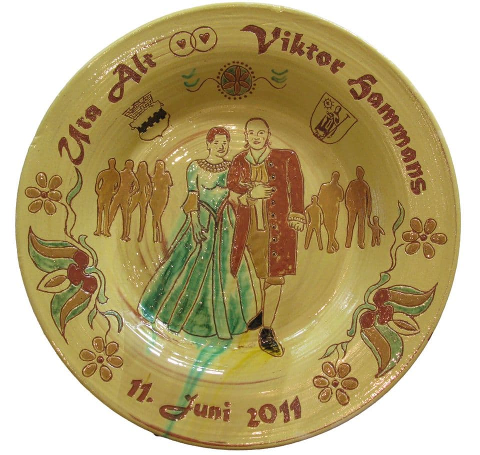 Hochzeitsteller mit Brautpaar im Ballkleid und Frack, dahinter Gäste als Schattenrisse, Namen und Datum „11. Juni 2011“ auf gelber Glasur.