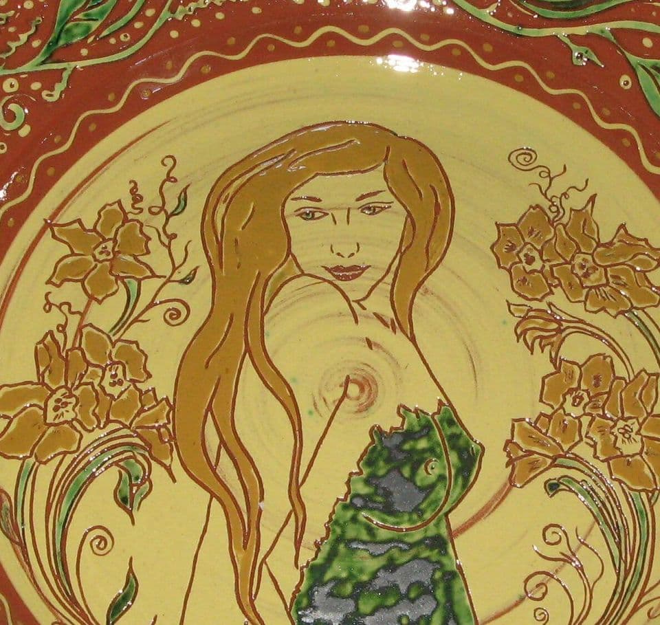 Detail des Jugendstiltellers: Gesicht und Haar der Frau, umgeben von Narzissen und feinen Ritzlinien.