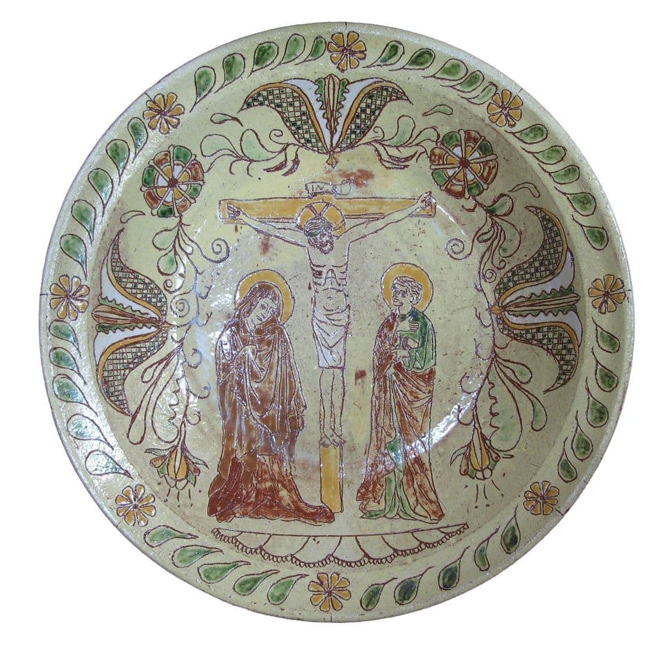 Teller mit Kreuzigungsgruppe, Maria und Johannes, darüber und daneben Blüten- und Palmettenornamente in Ritztechnik.