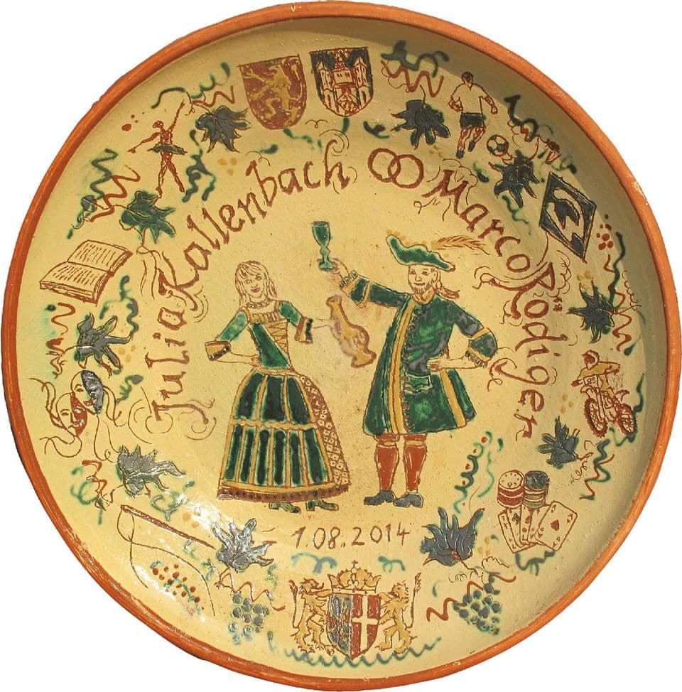 Hochzeitsteller mit Brautpaar in Tracht, umlaufender Schrift und kleinen Wappen, Ritzzeichnung auf gelbem Grund.