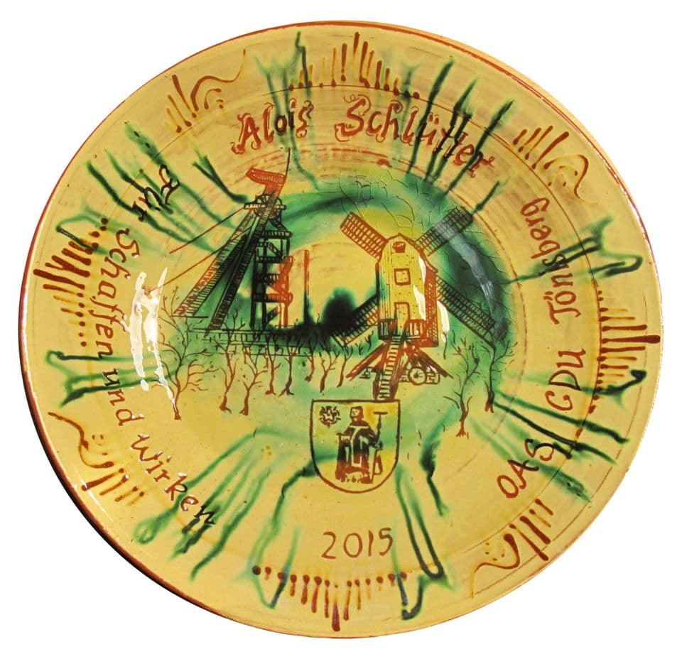 Jubiläumsteller mit Mühle, Wappen und Schriftband, grüne Glasur läuft strahlenförmig vom Spiegel zum Rand, Jahreszahl 2015.