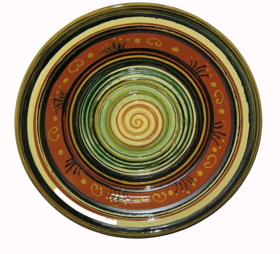 Teller mit Spirale im hellgrünen Spiegel, umgeben von dunklen Ringen und einem rotbraunen Rand mit gelben Punkten.