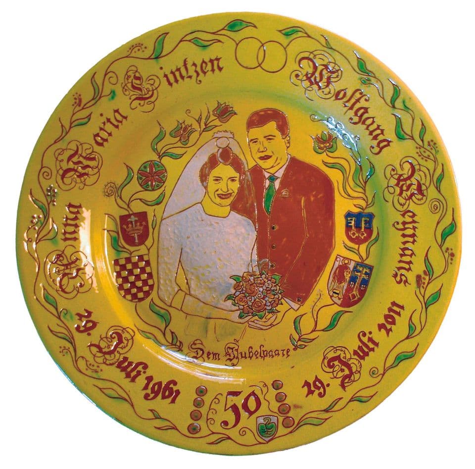 Goldhochzeitsteller mit Foto-Porträt eines Ehepaars in Ritztechnik, umgeben von Namen, Daten, der Zahl 50 und kleinen Wappen.